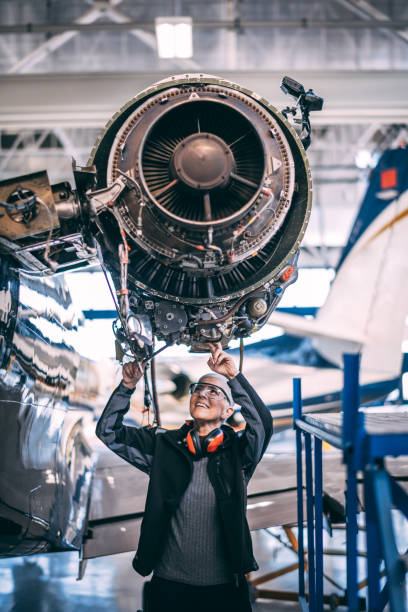 Senior female engineer doing some maintenance on an aircraft jet engine in a hangar.